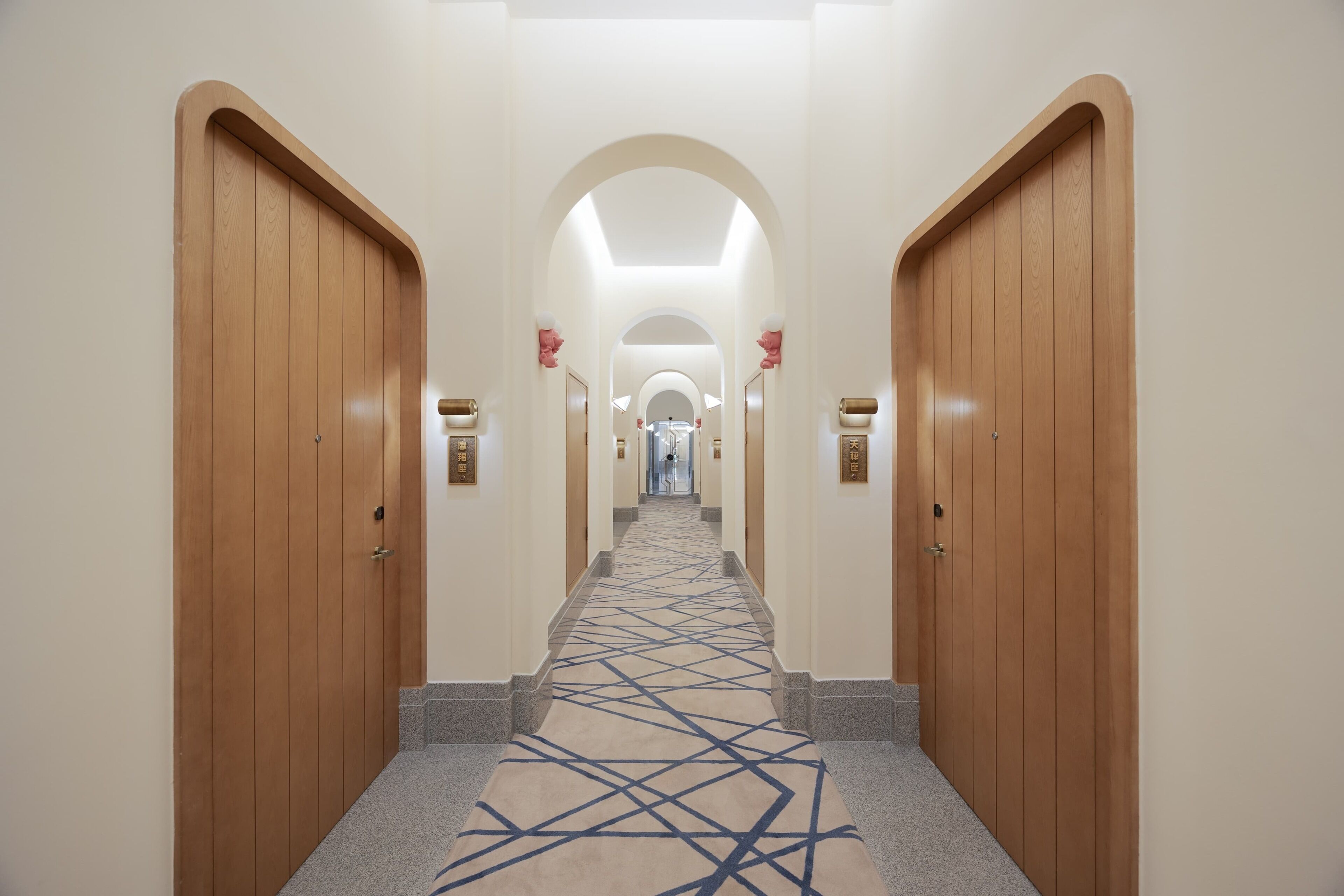 A hallway with wooden doors, a patterned carpet, and a central archway.