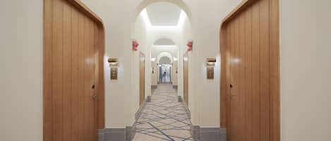 A hallway with wooden doors, a patterned carpet, and a central archway.