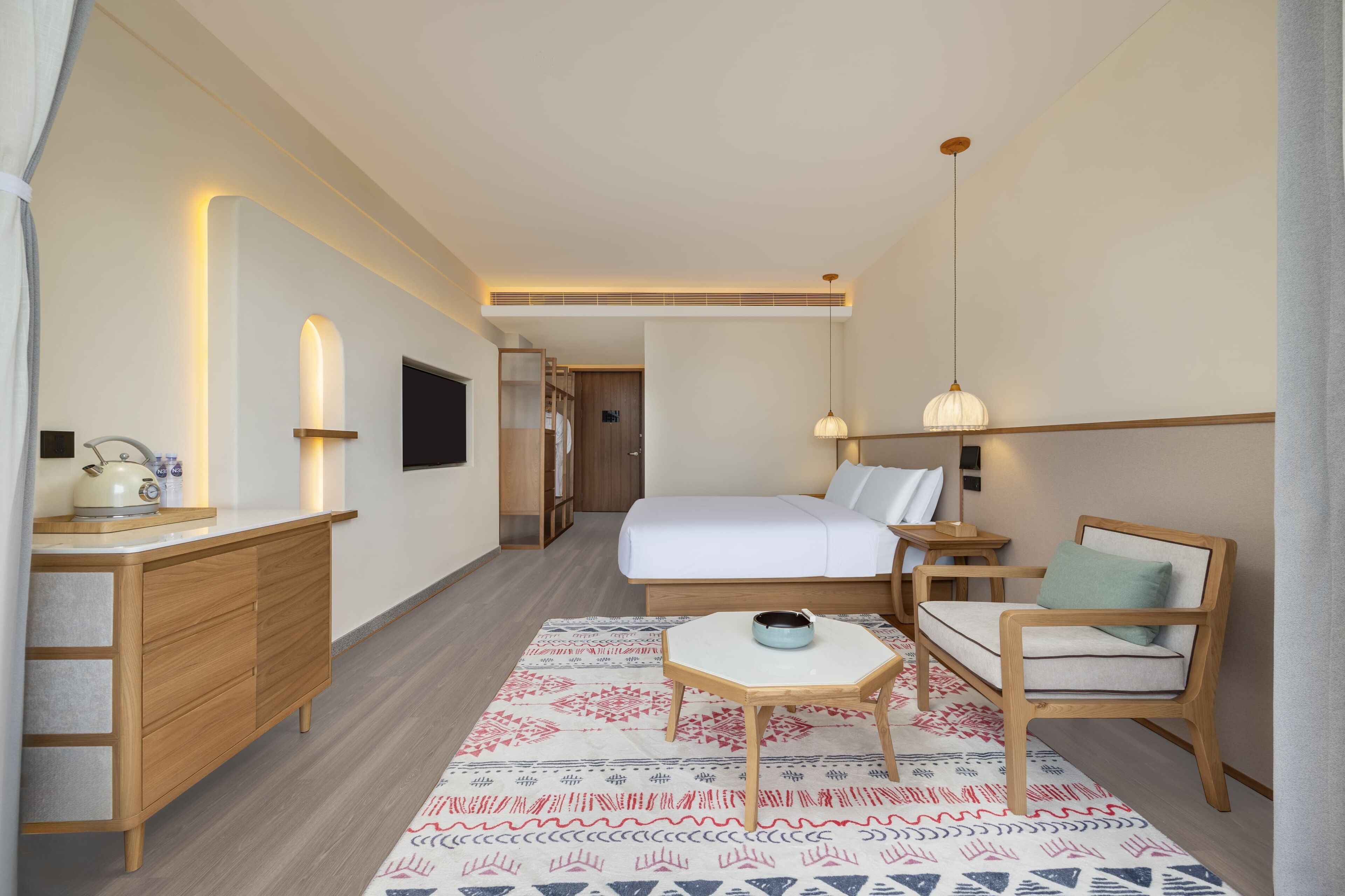 Une chambre d’hôtel comprenant un lit, une table de chevet, une chaise, un bureau et un tapis à motifs.