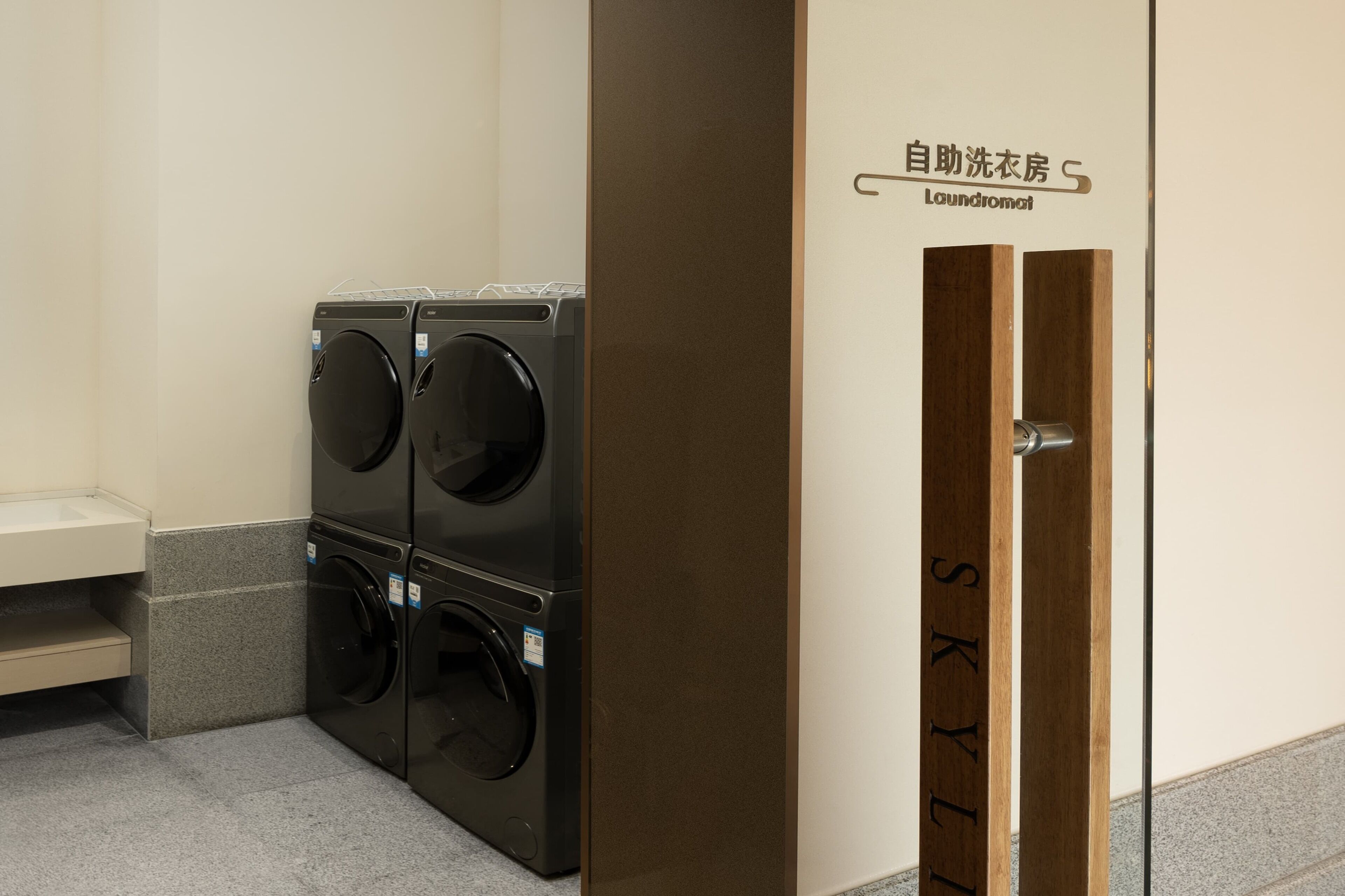 A laundry area with two stacked washing machines and a wooden door with a sign.