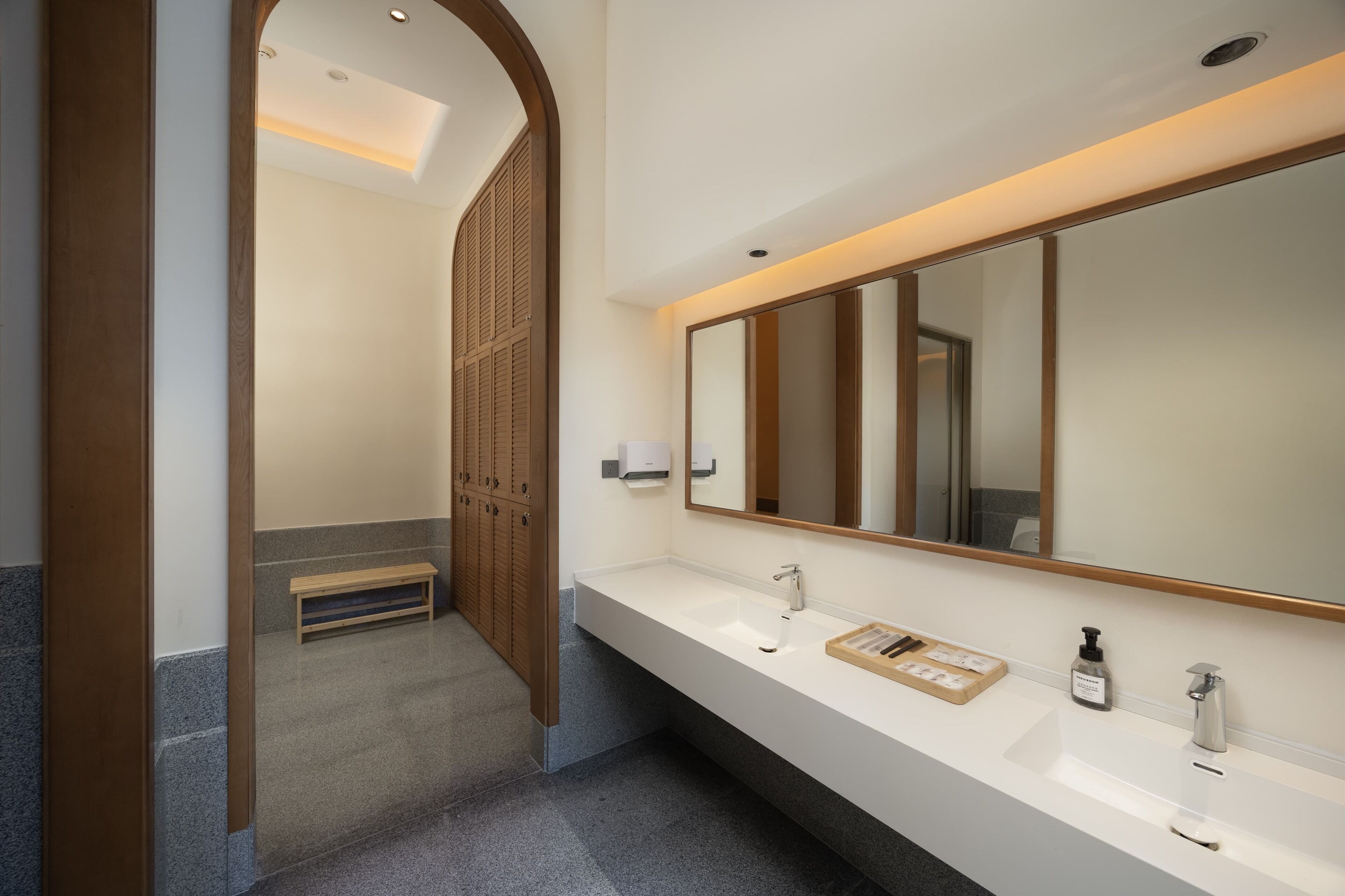 Un baño moderno con un tocador espacioso, un espejo grande y una puerta de madera.