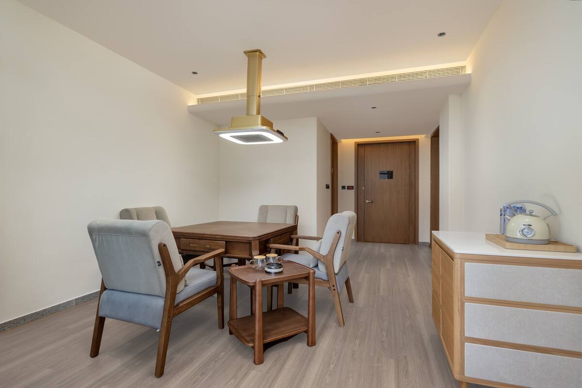 A modern dining area with a wooden table and chairs, a small side table, and a ceiling light fixture.