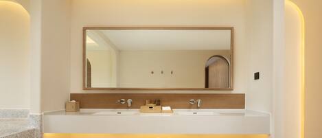A modern bathroom with a large mirror, two sinks, and a wooden vanity with towels.