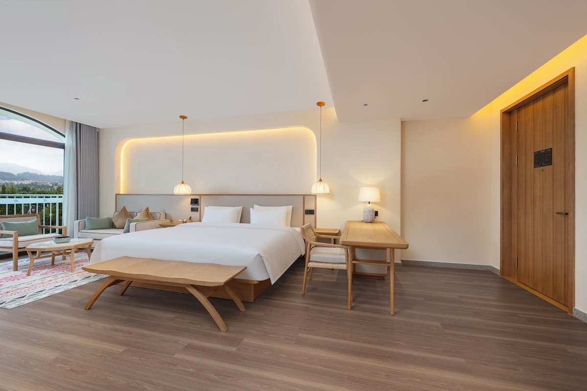 A modern hotel room with a large bed, a desk, and a view of the city.