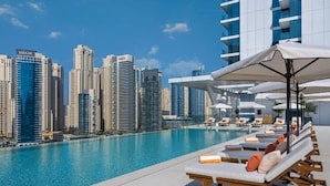A rooftop pool with lounge chairs and umbrellas, overlooking a cityscape with high-rise buildings. - EDEN’S Homes & Villas - VIDA Dubai Marina Residences (Dubai)
