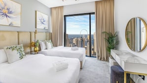 A hotel room with two beds, a desk, a large mirror, and a view of the cityscape. - EDEN’S Homes & Villas - VIDA Dubai Marina Residences (Dubai)