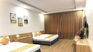 A hotel room with two beds, a desk, a TV, and a curtain. - White Hotel (Thanh Vinh)