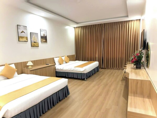 A hotel room with two beds, a desk, a TV, and a curtain. - White Hotel (Thanh Vinh)