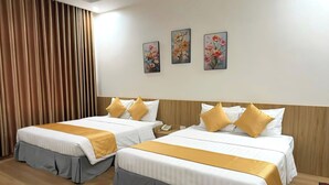 A hotel room with two beds, a wooden headboard, a telephone, and three floral paintings on the wall. - White Hotel (Thanh Vinh)