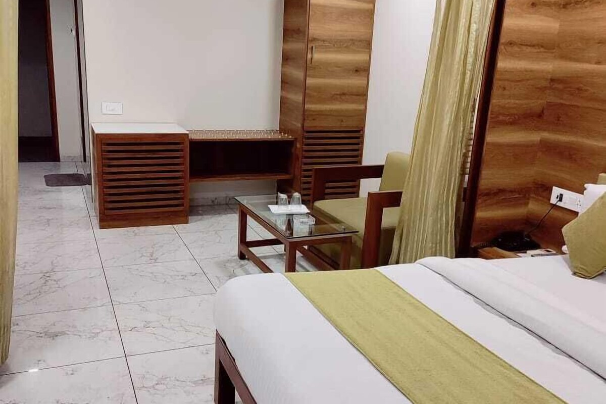 A hotel room with a bed, a desk, a chair, a wardrobe, and a small table.