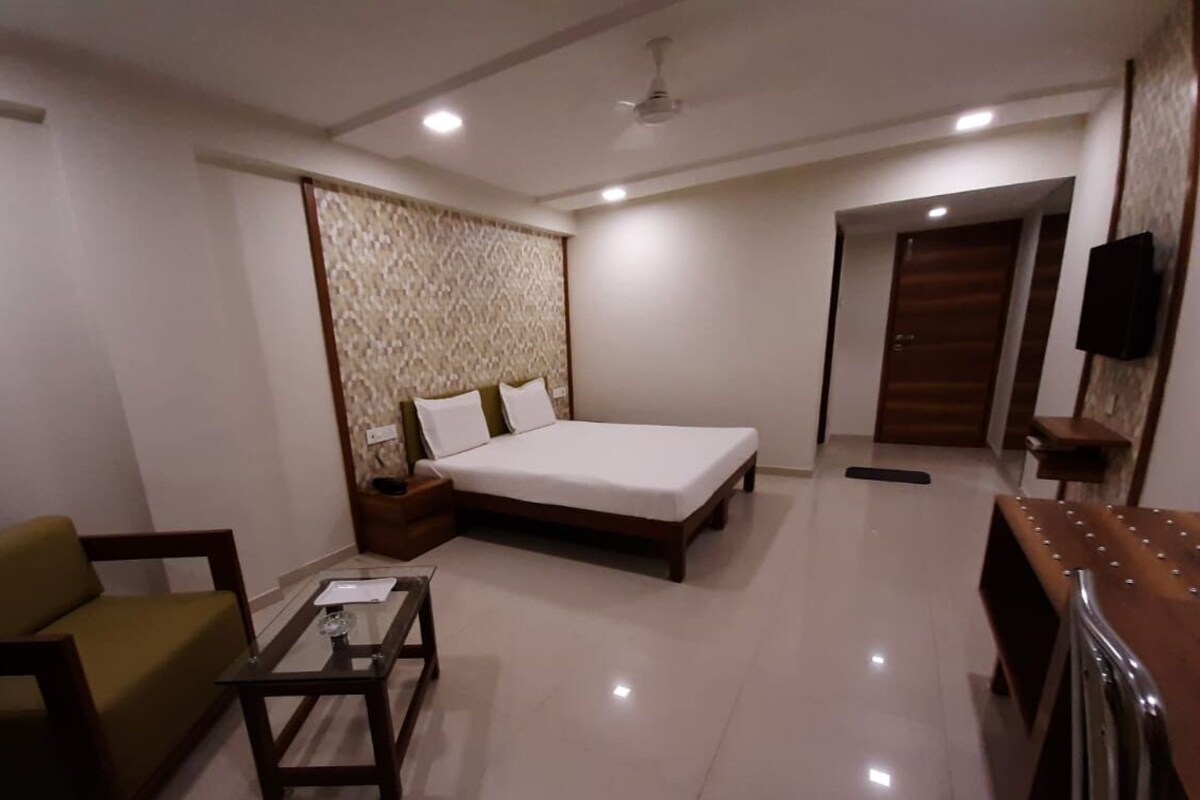 A bedroom with a bed, a sofa, a coffee table, a TV, and a wardrobe.