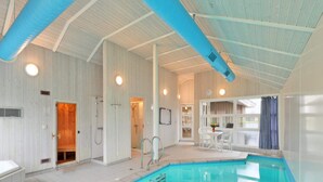 An indoor swimming pool with a tiled floor, a shower area, and a seating area with a table and chairs. - 4 Star Holiday Home in Ottendorf (Otterndorf)