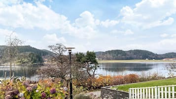 Vista para o lago com cerca branca, poste de luz e diversos arbustos.