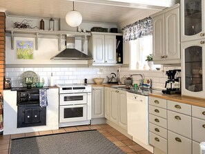A kitchen with white cabinets, a stove, an oven, a sink, and a coffee maker. - 5 Star Holiday Home in Uddevalla (Uddevalla)