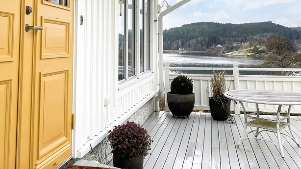 A wooden deck with a yellow door, potted plants, and a table. - 5 Star Holiday Home in Uddevalla (Uddevalla)