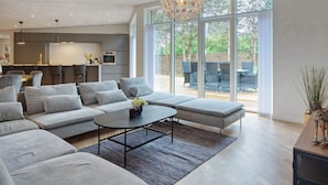 Ein modernes Wohnzimmer mit einem Ecksofa, einem Couchtisch und einem Essbereich mit Bar.