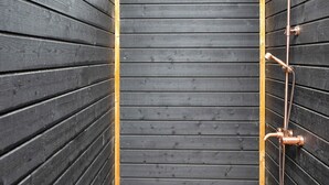 Eine Holzhütte mit einer Duschkabine aus Metall.