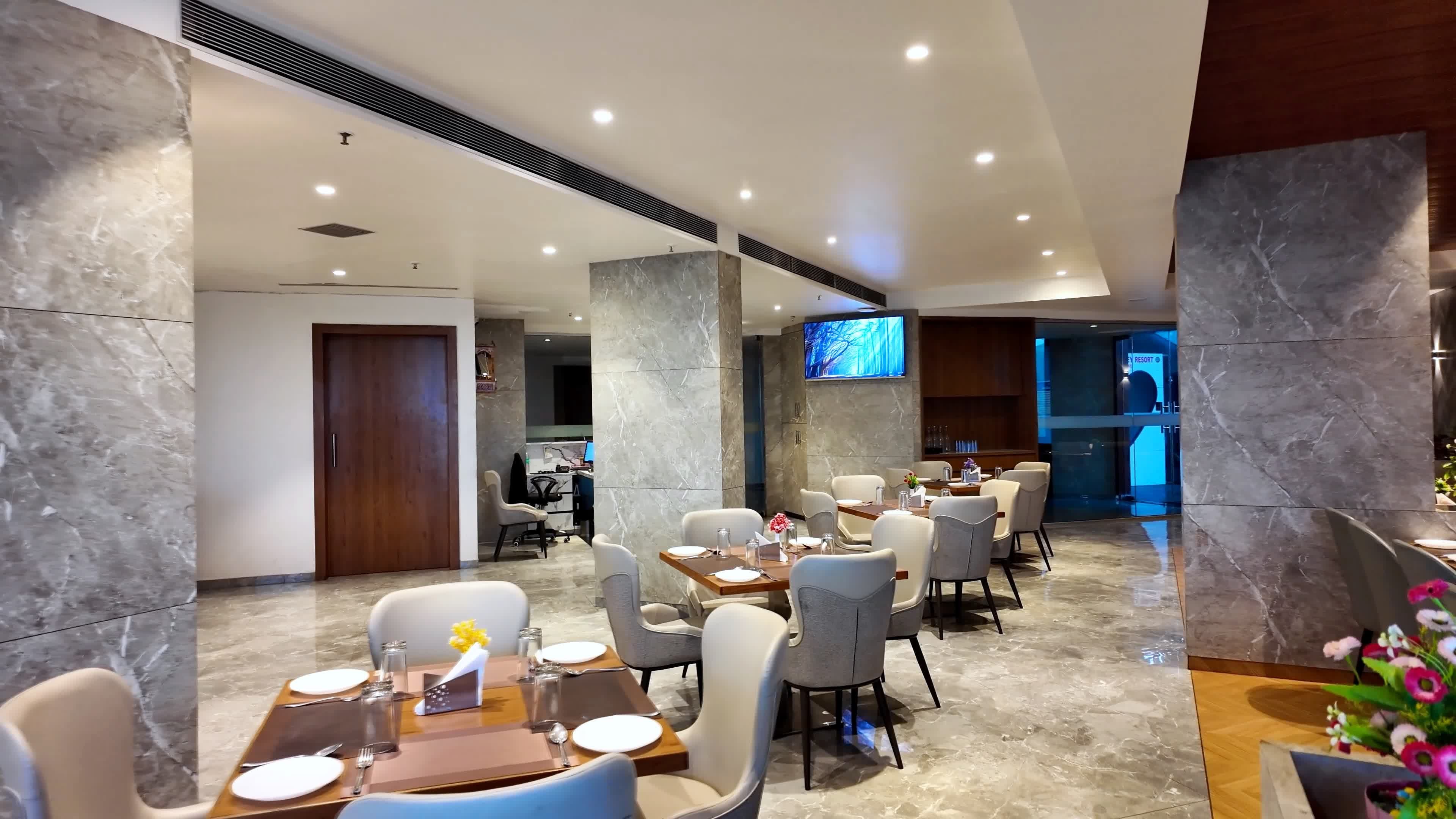 A modern hotel lobby with marble flooring, a reception desk, and a seating area with tables and chairs.