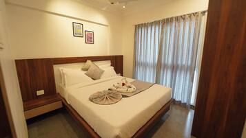 A hotel room with a large bed, a ceiling fan, and a window with curtains.