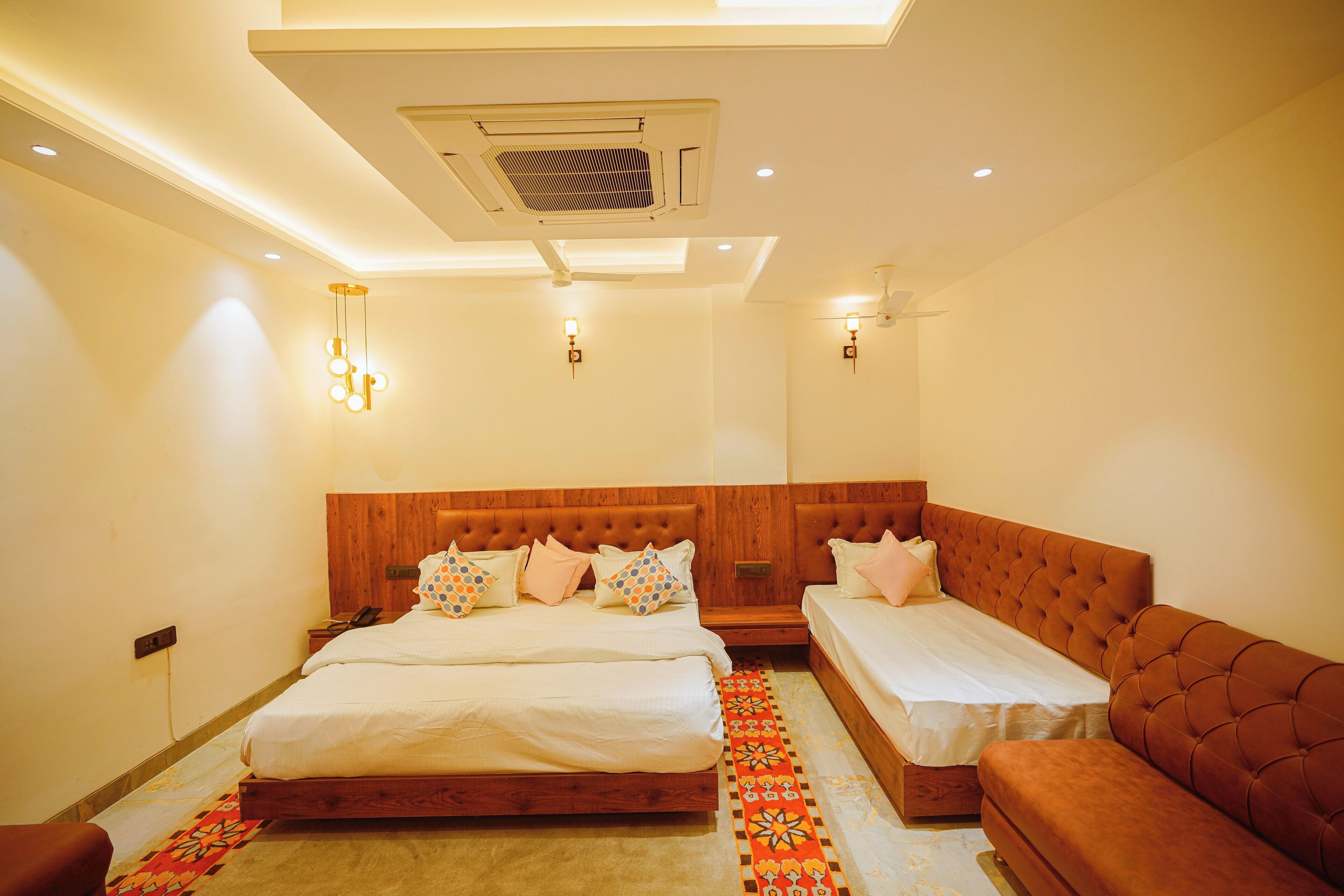A hotel room with a large bed, a smaller bed, a sofa, and a ceiling fan.