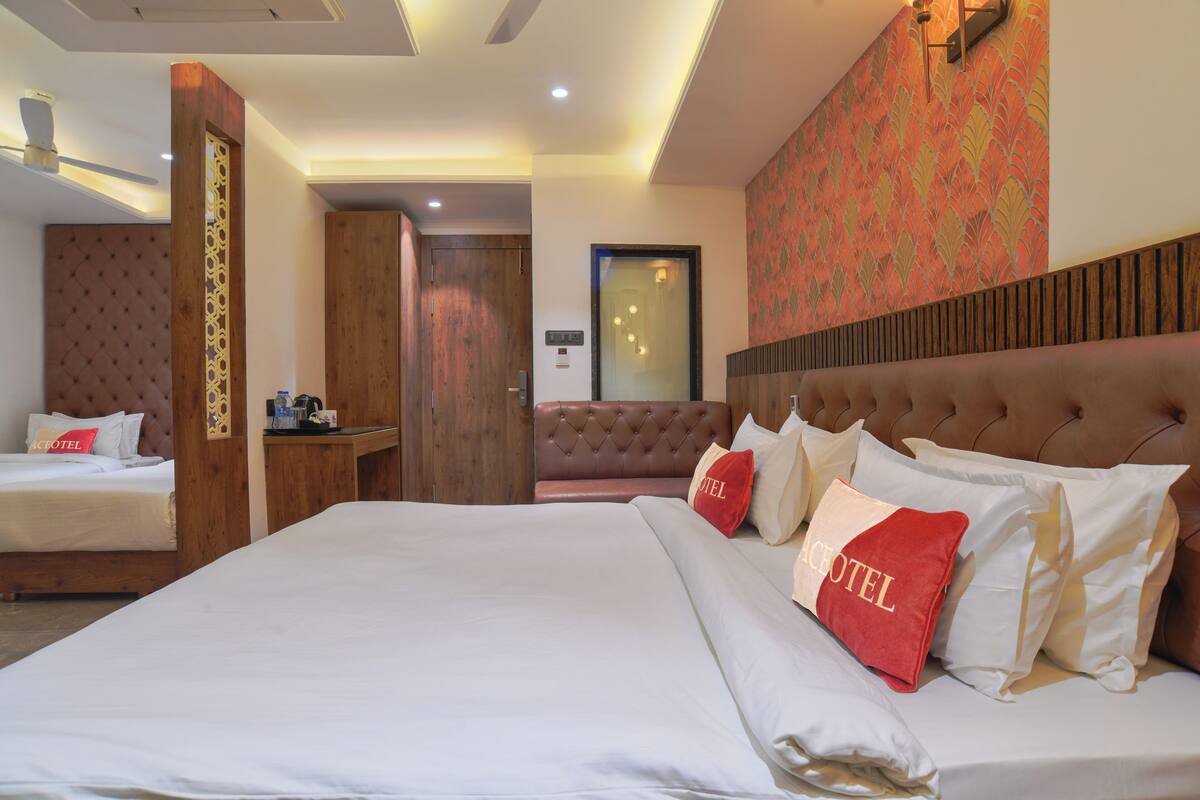 A hotel room with a large bed, a separate seating area, a wooden headboard, and a patterned wall.