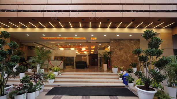A hotel entrance with a modern design, featuring a marble reception desk, potted plants, and a tiled floor. - Hotel Guru Kripa, Bhopal (Bhopal)