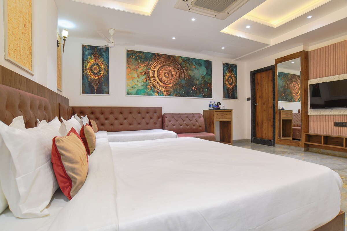 A spacious bedroom with a large bed, a seating area, and artwork on the walls.