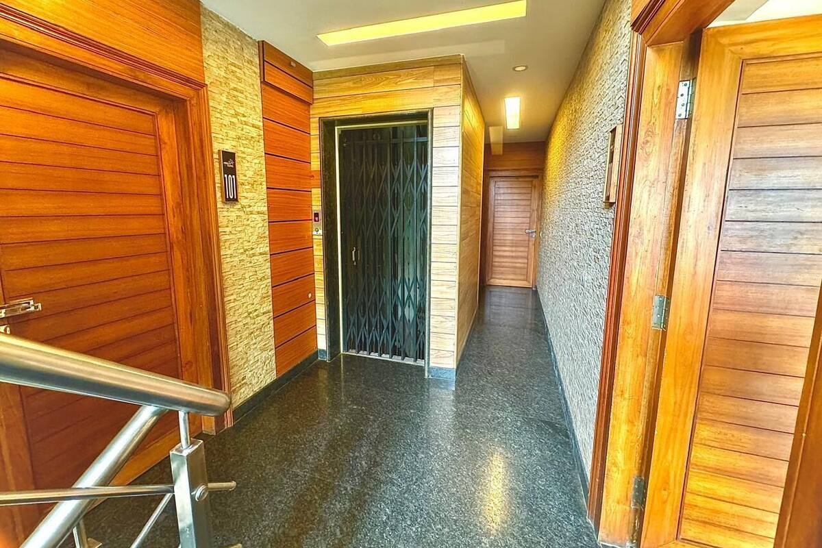 A hotel hallway with wooden doors, a metal railing, and a textured wall.