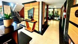 A modern hotel lobby with a staircase, a reception desk, and a decorative wall.