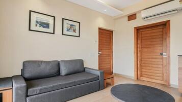 A modern living room with a grey sofa, a small table, and two wooden doors.