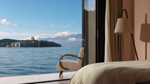 A hotel room with a large window offering a view of a body of water and a distant island.