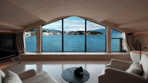 Amplia sala de estar con un ventanal que ofrece vistas a un cuerpo de agua y montañas distantes.