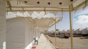 A covered outdoor area with white canopies, rows of chairs, and tables arranged for dining. - Desert Gold Resort (Jaisalmer)