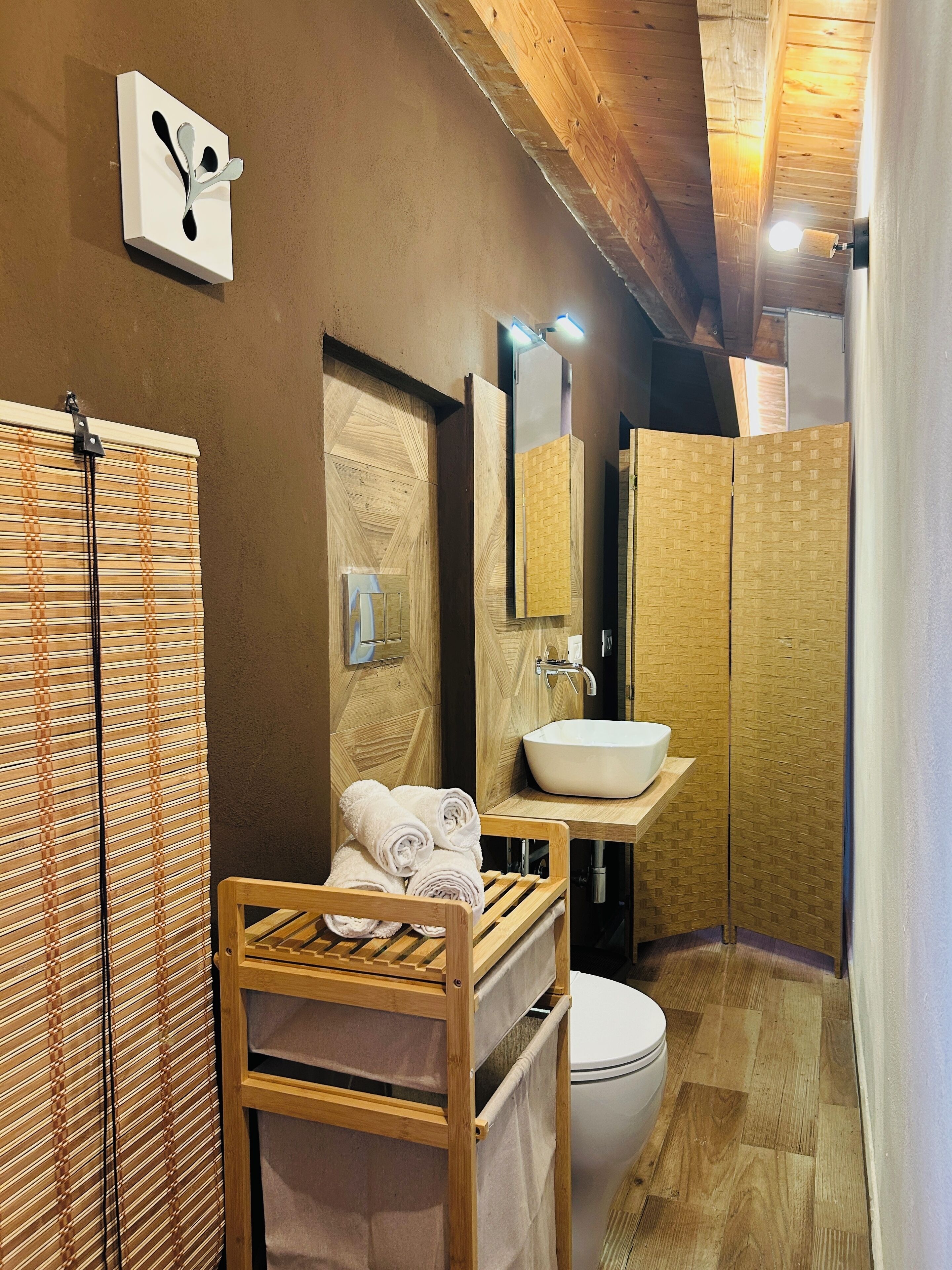 A bathroom with a wooden vanity, a sink, a toilet, and a shower area.