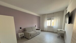 A minimalist living room with a sofa, a small table, and a TV mounted on the wall. - Sve's House (Roma)