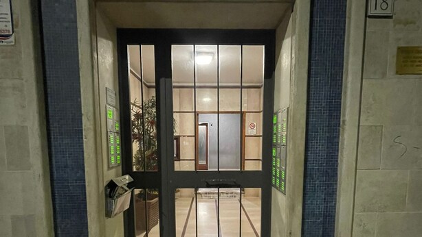 A hotel entrance with a tiled floor, a metal door with a glass panel, and a number sign indicating the entrance. - Sve's House (Roma)