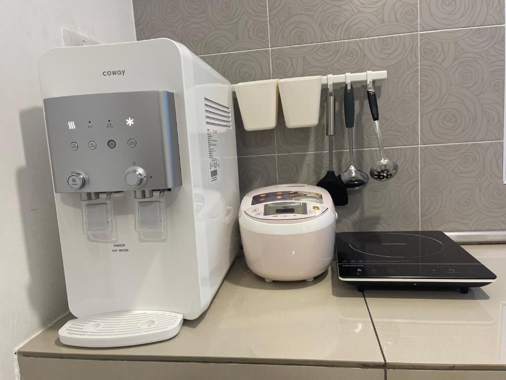 A kitchen with a water dispenser, a rice cooker, and a black induction cooktop.