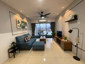 Una sala de estar moderna con un sofá azul, una mesa de centro, un televisor y un ventilador de techo.