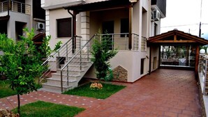 A modern building with a covered outdoor area, a staircase, and a paved walkway. - Amalia Lux Villas (Volvi)