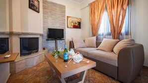 A modern living room with a fireplace, a sofa, a coffee table, and a TV. - Amalia Lux Villas (Volvi)