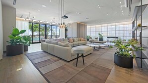 A spacious living area with a large sofa, coffee table, and potted plants. - Stylish 2BR with Pool & Balcony (Miami)