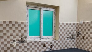 Una cuina amb taulell negre, una finestra amb dibuix a quadradets i un paperer blau.
