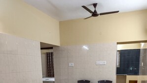 Una habitació amb parets beix, un paviment amb dibuixos, dues cadires i un ventilador de sostre.
