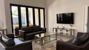 Una sala de estar moderna con un sofá de cuero, una mesa de centro de vidrio y un televisor de pantalla plana montado en la pared.