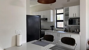 Una cocina moderna con armarios blancos, un refrigerador negro, un lavamanos de acero inoxidable y un microondas negro.