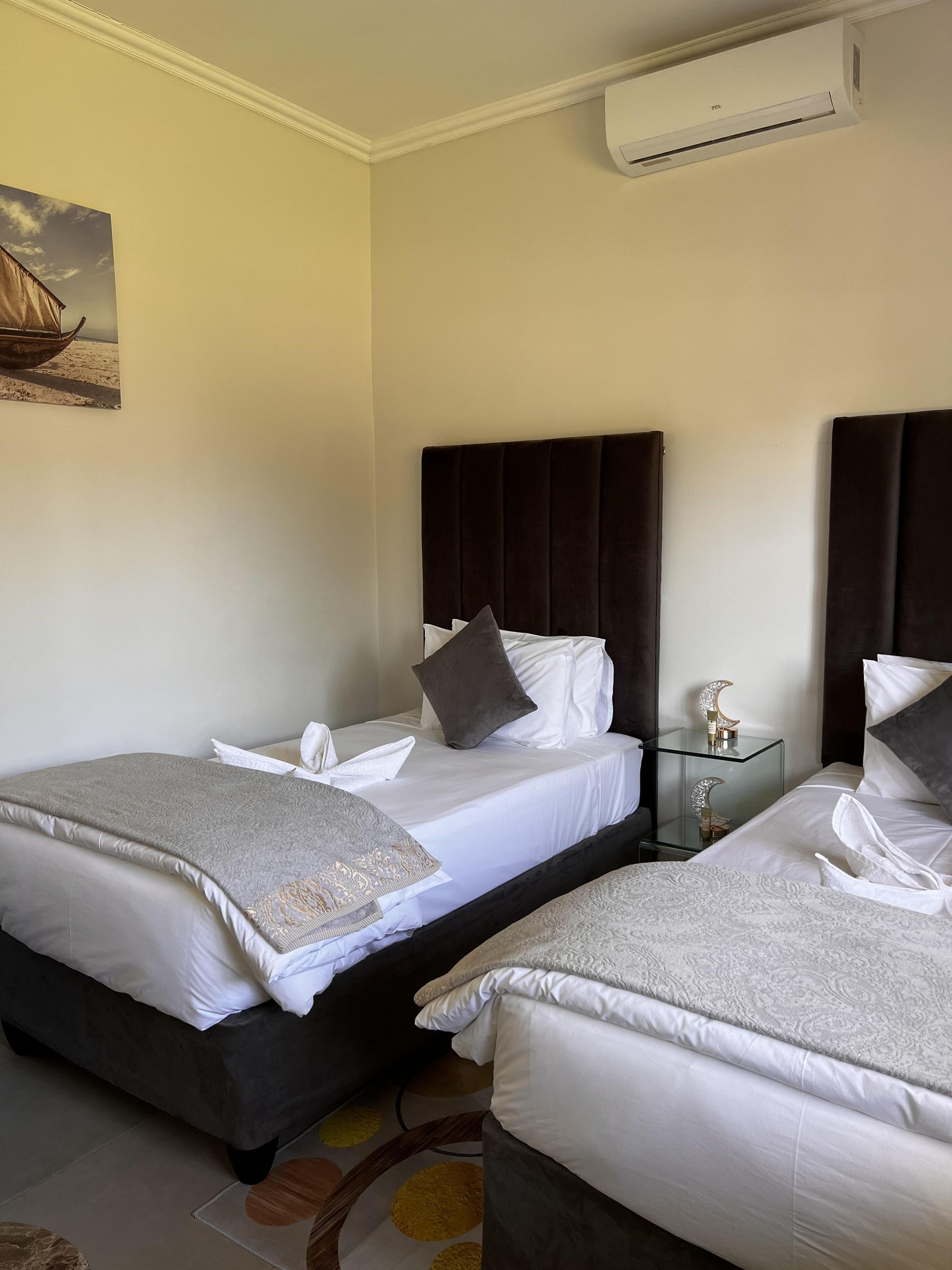 A hotel room with two beds, a nightstand, and an air conditioning unit.