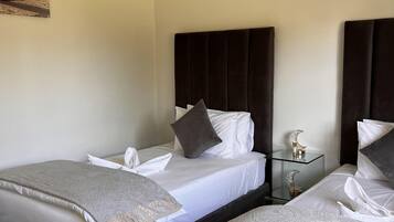 A hotel room with two beds, a nightstand, and an air conditioning unit.