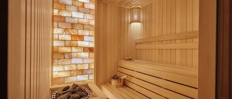 A wooden sauna with a stone wall and benches.