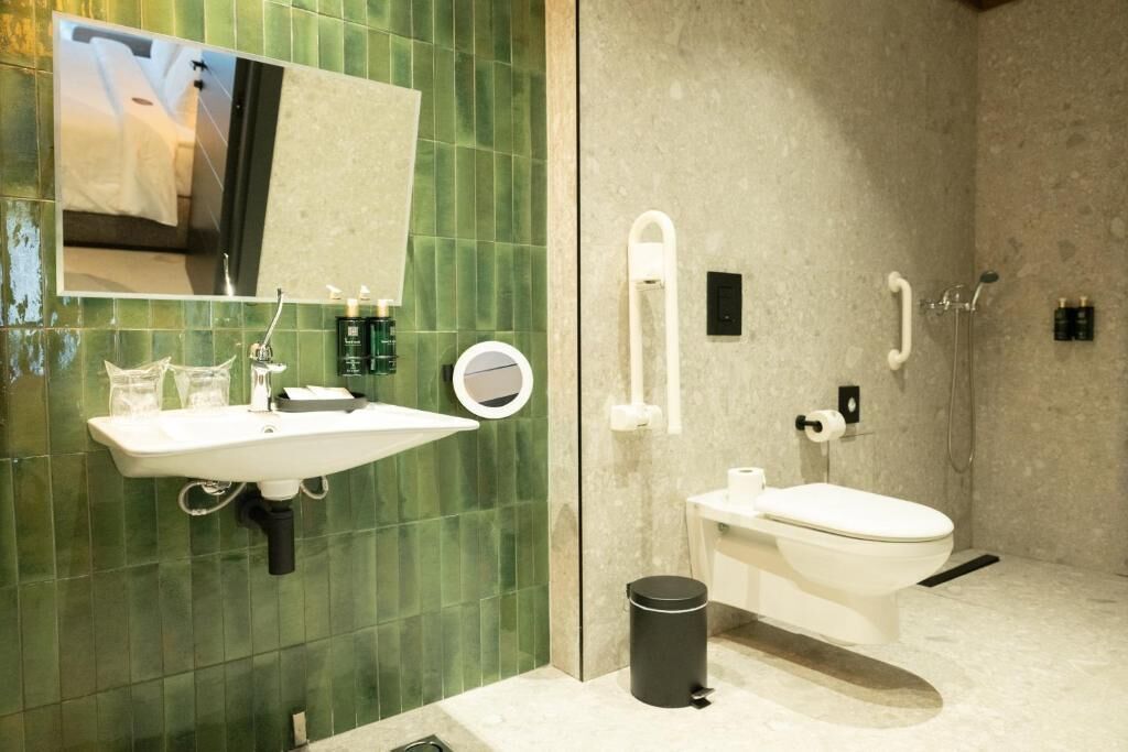 Un bagno con lavandino, specchio, WC e doccia.
