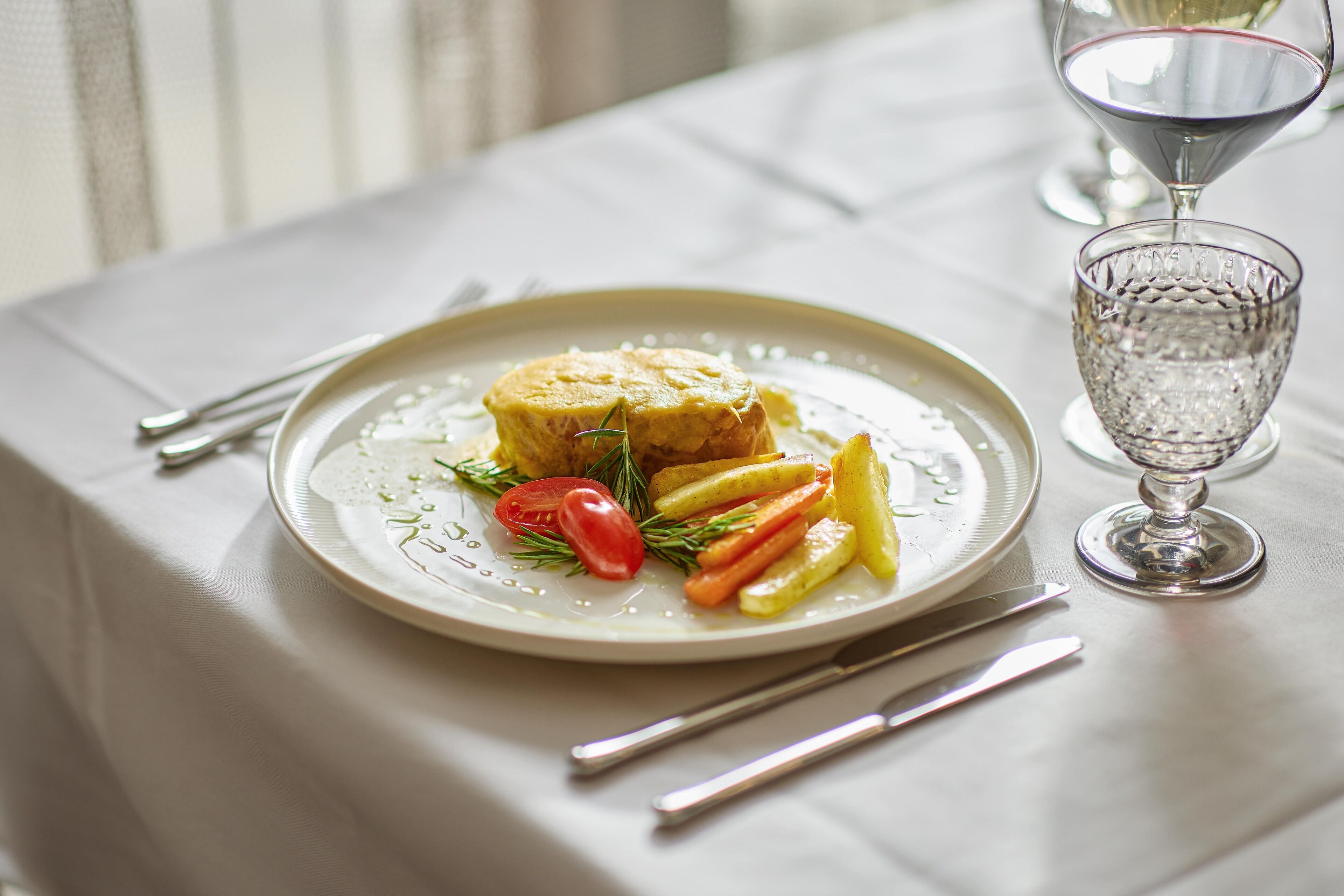 A plate of food with a glass of wine on a table.